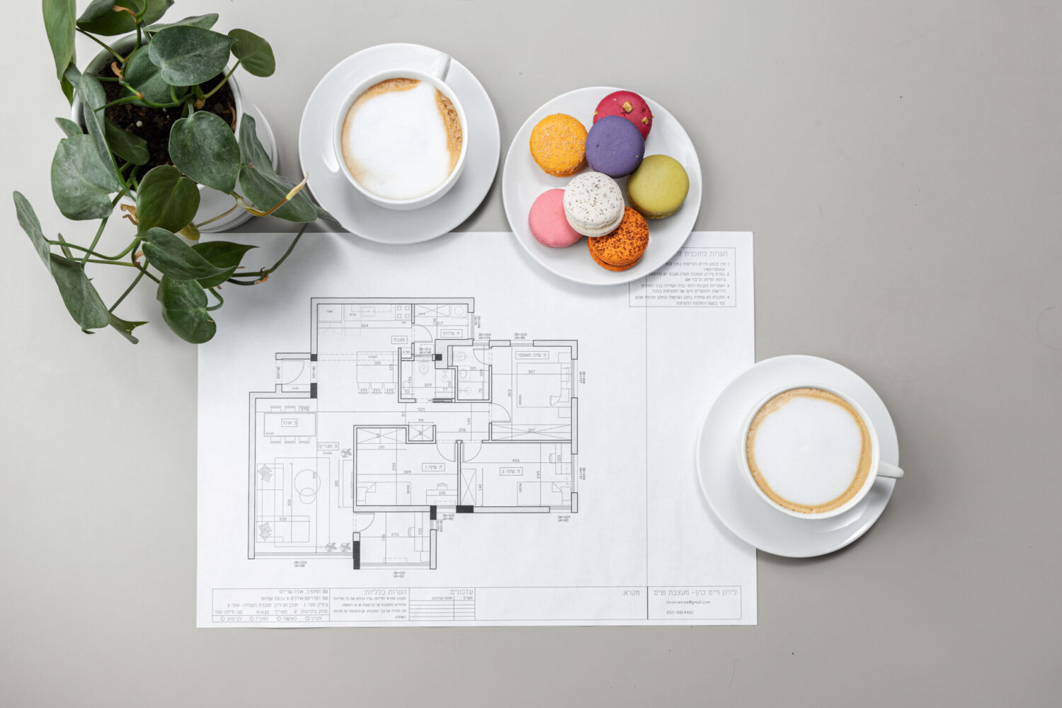 תמונה של שרטוט תכנית דירה עם כוסות קפה ועוגיות